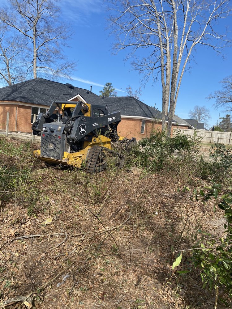 John Deere skid steer with mulcher clearing dense underbrush