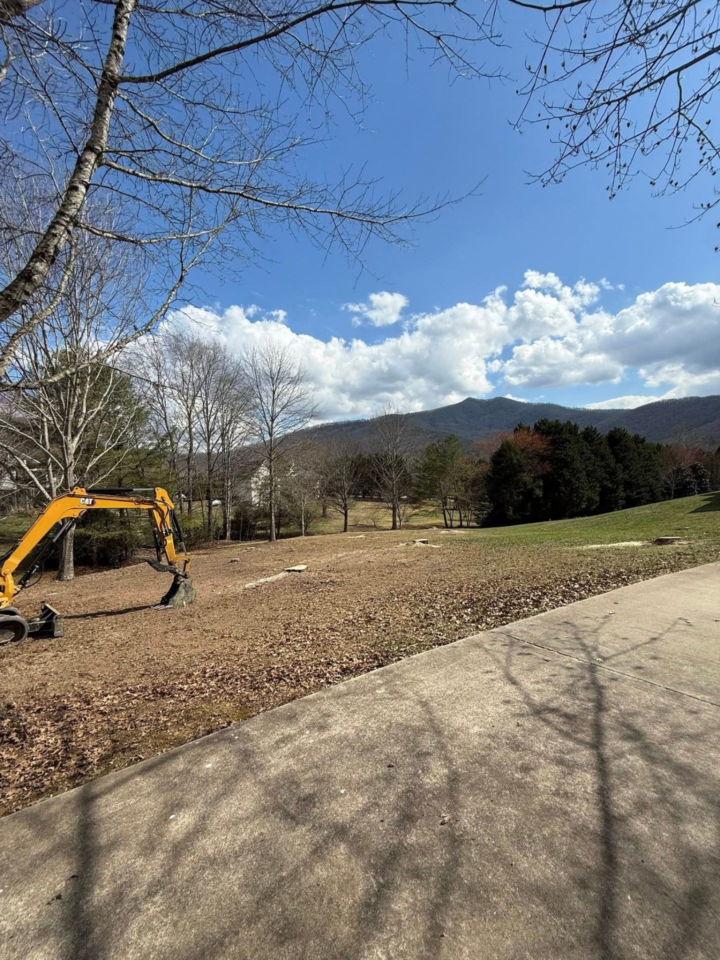 Mountain-view land clearing site with CAT excavator